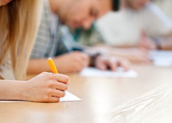 Studenten schreiben eine Klausur im Hörsaal, Prüfungsformen im IU Fernstudium