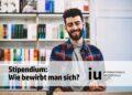 Student lächelt, Bibliothek, Bewerben für ein IU Stipendium