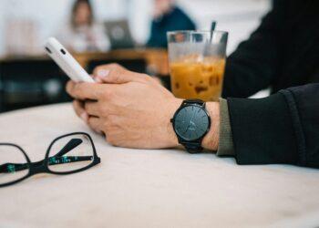 Student sitzt in einem Café am Tisch und pflegt seinen Instagram-Shop übers Smartphone